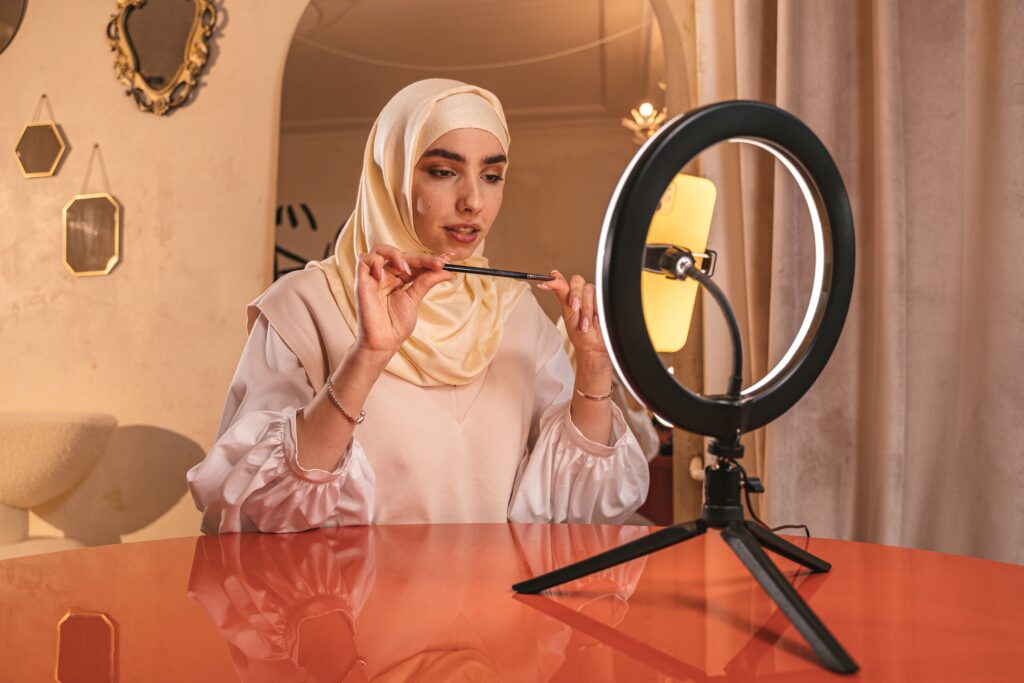 A young woman in a hijab using a ring light to make a TikTok